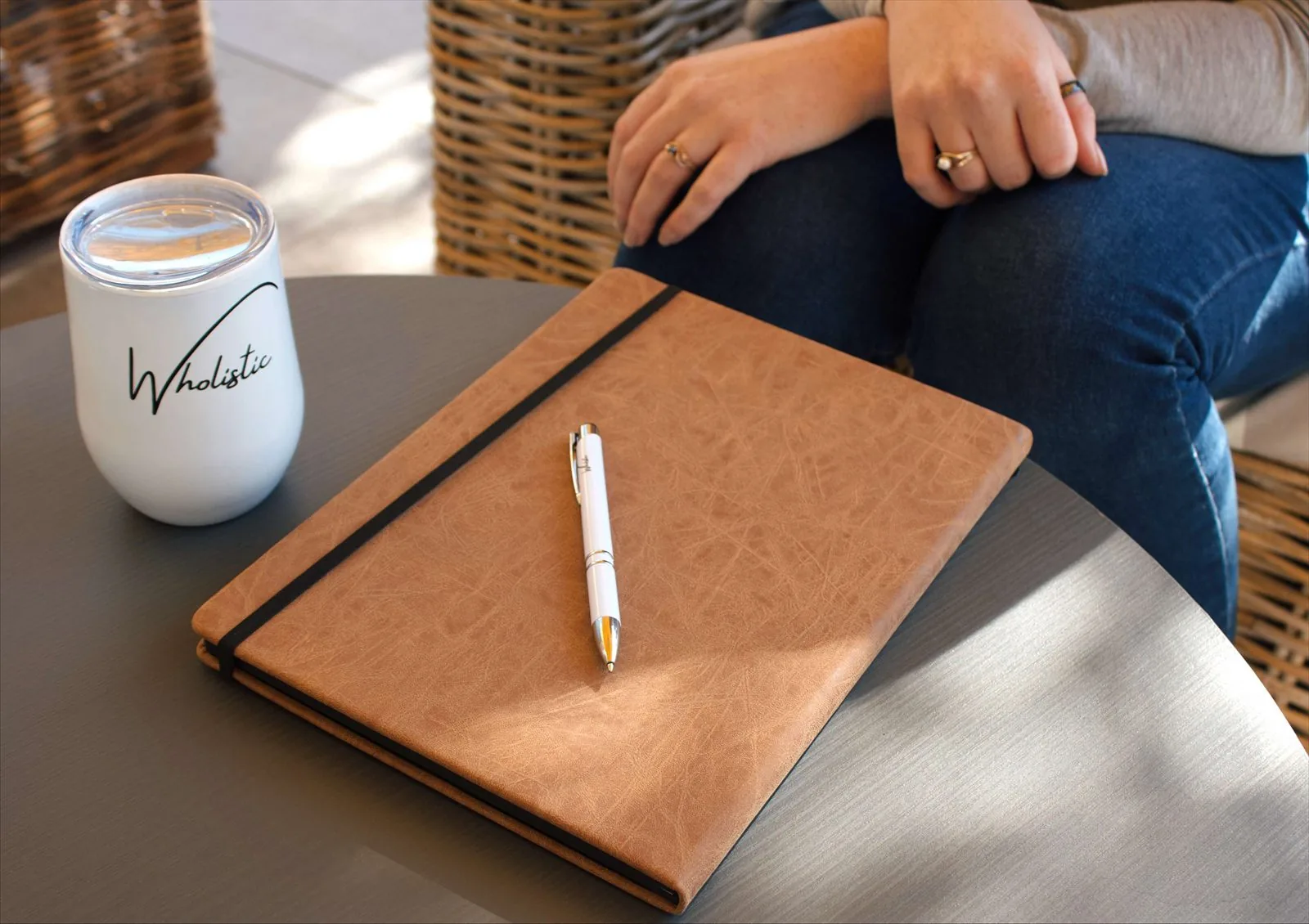 A notebook, pen and Wholistic mug on a table between sessions